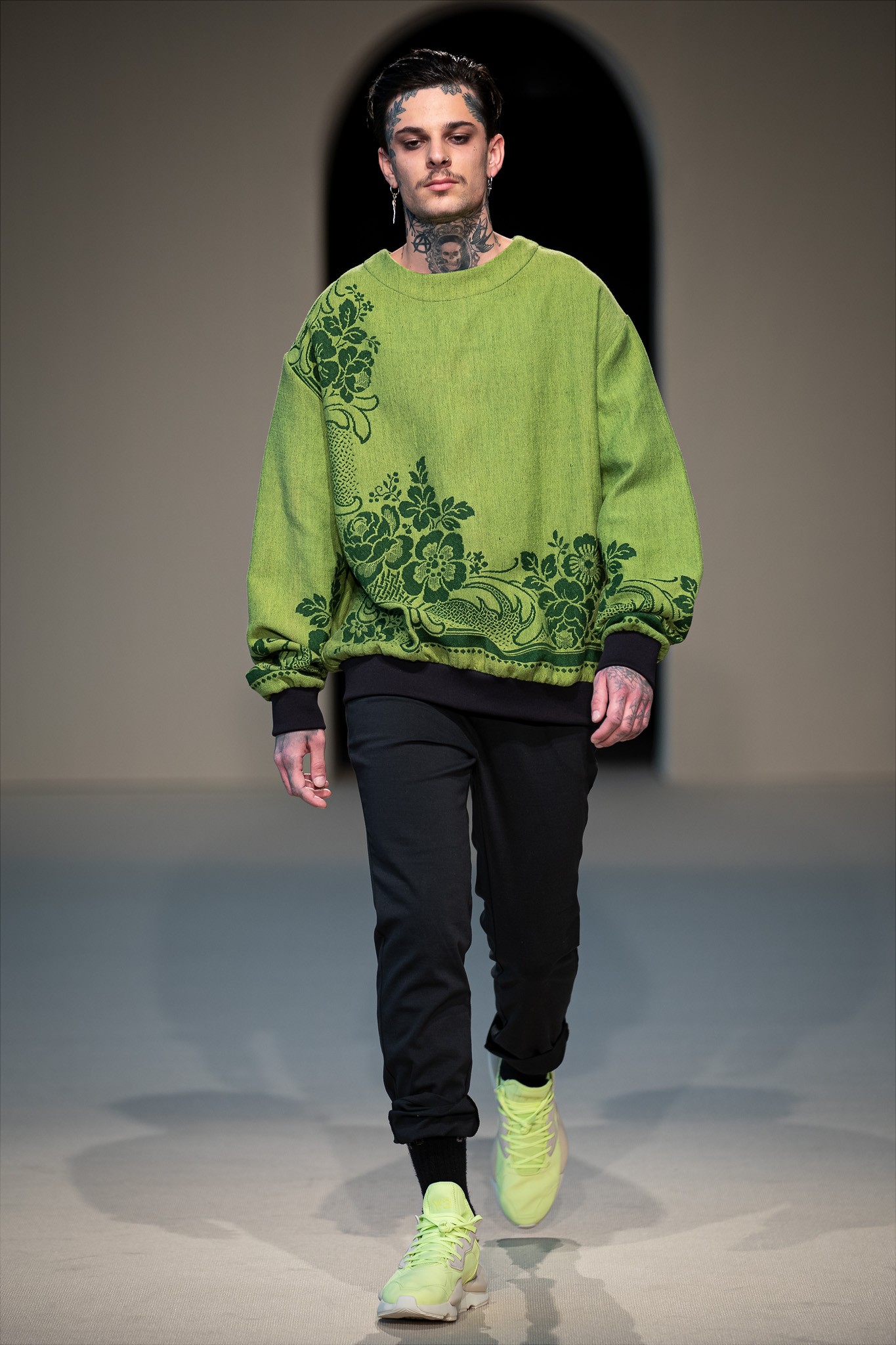 A bársonyos virágmotívumos applikációk vidéki jelleget kölcsönöznek a Laurus névre keresztelt pulóver modern szabásának, míg a gazdag zöld árnyalatok a természetet idézik. A pulóver anyagát körülbelül 80 évvel ezelőtt Magyarországon gyártották, és eredetileg gobelinre használták. Dora Zsigmond 2022 tavasz-nyár