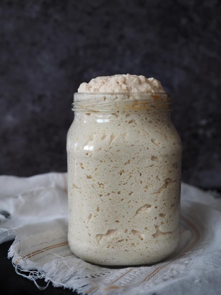 Aktív, érett kovász egy átlátszó üvegben – az erjedés jelei: buborékok, enyhén savanykás illat és látható emelkedés.