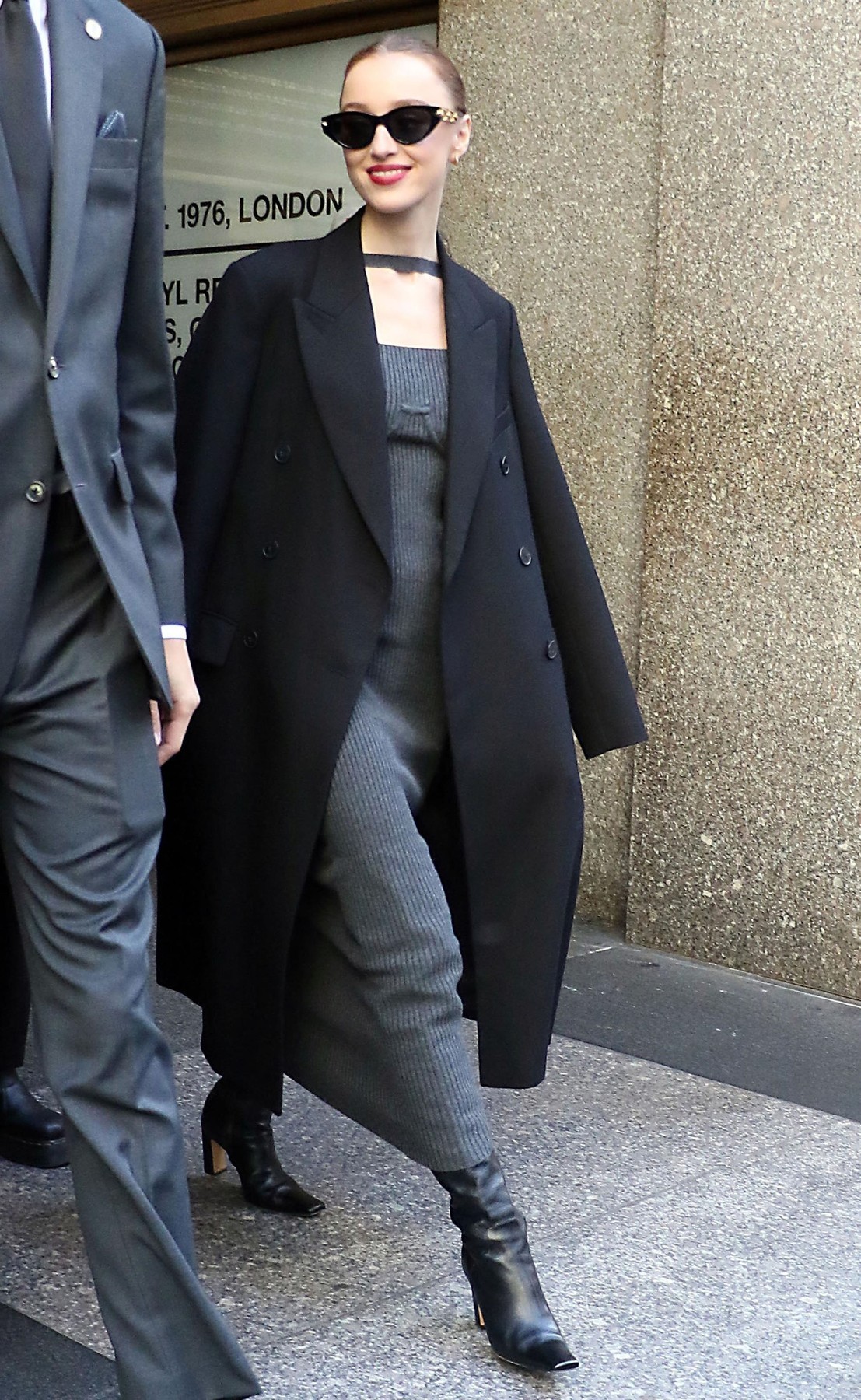 Phoebe Dynevor New Yorkban, a The Kelly Clarkson Show felvételéről távozva került a fotósok elé. A Bridgerton Daphne Bridgertonját alakító színésznő egy elegáns, bordázott szürke ruhát viselt, amelyet fekete kabáttal és bőr csizmával párosított. A letisztult, modern összeállítás jól mutatja, hogy a színésznő a hétköznapokban is kifinomult stílust képvisel – még ha ez távol is áll a sorozat romantikus, régens kori ruháitól.