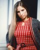 Barbra Streisand 1965 körül, egy bohém hangulatú, piros-fehér mintás ruhában, hosszú, egyenes hajjal – megjelenése tökéletesen tükrözi a korszak szabadszellemű stílusát.