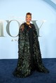 Queen Latifah királynői megjelenéssel hódította meg a vörös szőnyeget ebben a lenyűgöző Naeem Khan ruhakölteményben. A színésznő egy letisztult, elegáns fekete alapruhát választott, amely fölé egy egészen monumentális, földig érő köpenyt terített. Ez a különleges darab a vállrésznél finom, pókhálószerű fekete gyöngyhímzéssel indult, majd sűrűn varrt, méregzöld és kék árnyalatú tollakban végződött.  Az uralkodói összképet egy magasan feltűzött, elegáns konty és lógós fekete fülbevalók varázsolták hibátlanná.