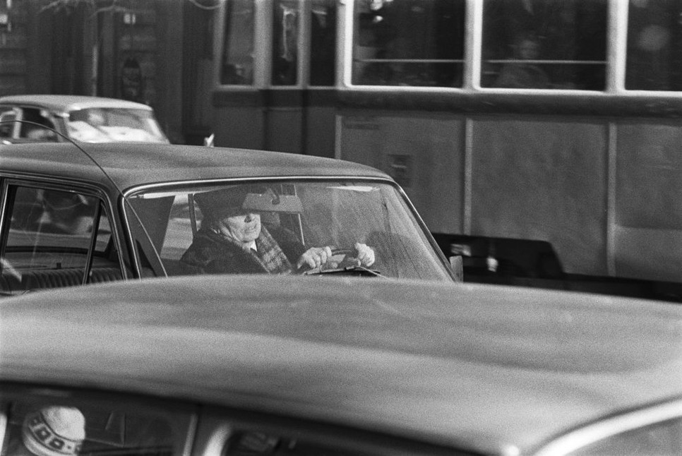 Egy autóban ülő alak tekintete túlmutat az ablakon – a fotó nemcsak a fizikai, hanem a belső utazás pillanatát is megragadja, finom melankóliával és emberi közelséggel.