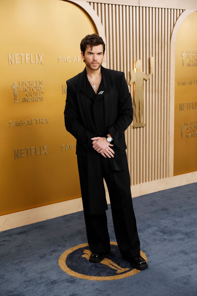 Luke Newton egy fekete, dupla gombolású blézert viselt, amely alá egy fekete inget húzott. Megjelenését egy hosszú, fekete sállal és egy gyémánt brossal tette teljessé, amely a zakó hajtókáján kapott helyet, finom csillogást adva az összeállításnak. Ez a bross a nemi identitás szimbólumait ábrázolta, ezzel kifejezve támogatását a transznemű közösség iránt.