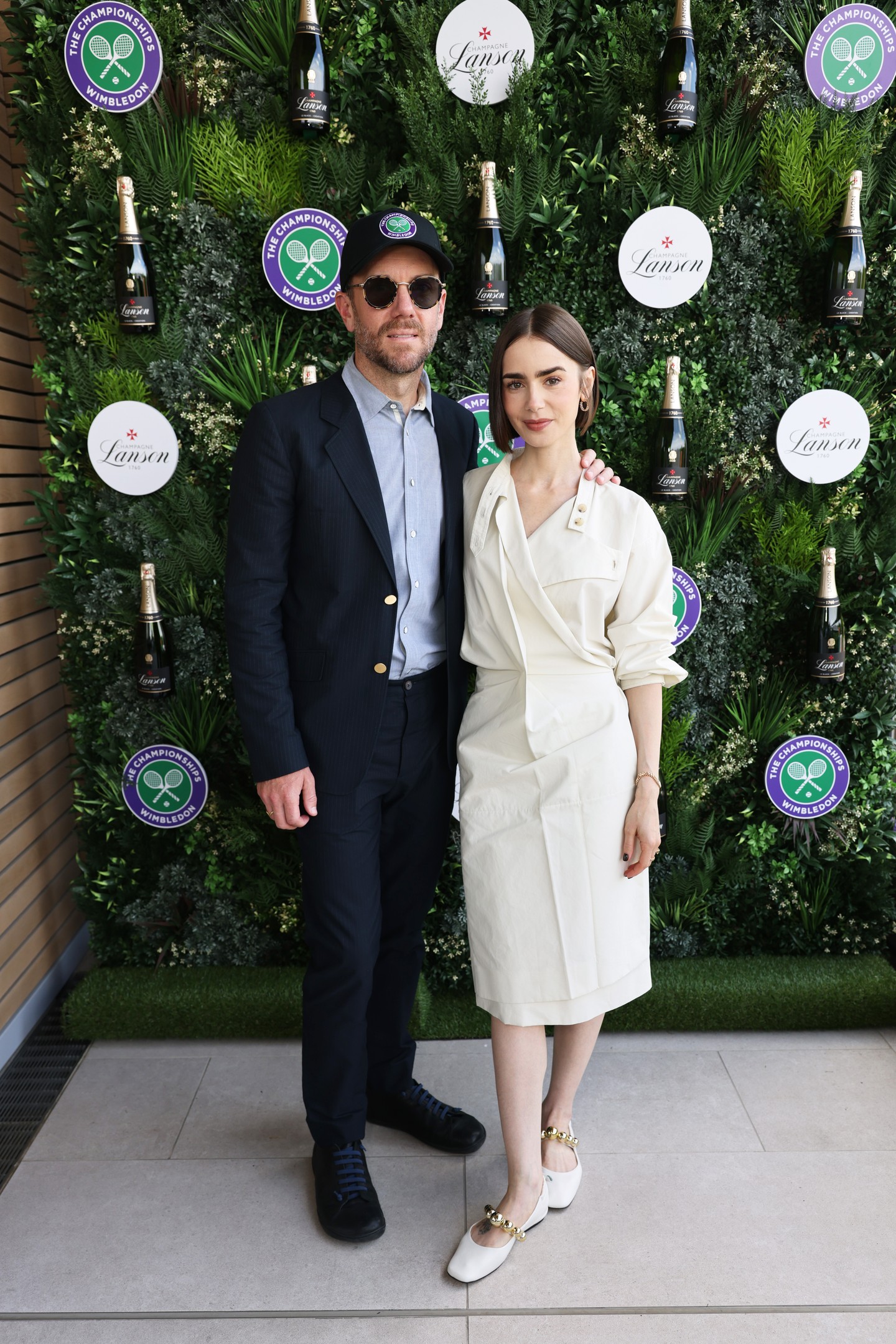 Lily Collins vasárnapi wimbledoni szereplését egy olyan megjelenéssel zárta, amely a finom kontrasztokra és egy látványos, lapos cipőre helyezte a hangsúlyt. Egy lenge, krémszínű ruhában, valamint fehér bőr Mary Jane cipőben jelent meg a Souliers Martineztől.