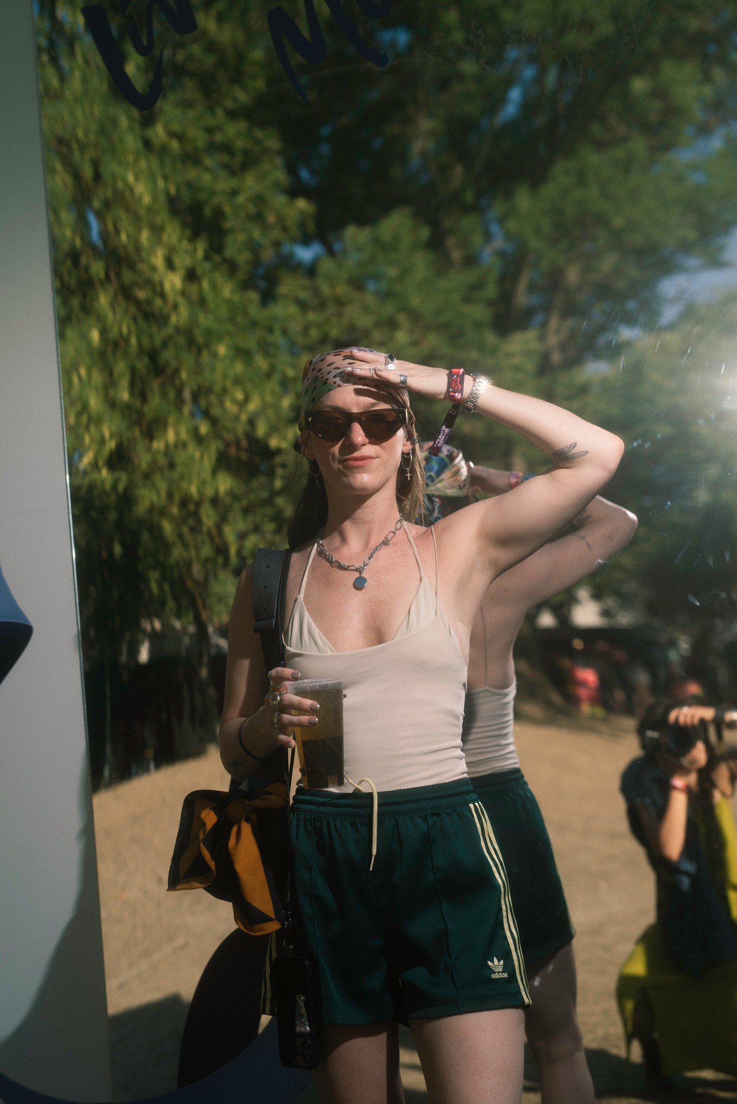 A sort, top és bikinifelső hármasa a fesztivál–streetwear hibrid stílust képviseli, amely egyszerre nyújt kényelmet és idézi meg a trendi vintage hangulatot. A mintás fejkendő és a markáns nyakláncok pedig boho, '90-es éveket felidéző réteggel teszik teljessé az összhatást.