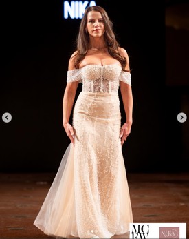 A 2025-ös milánói divathéten egy vállvillantós, gyöngyökkel díszített, felül áttetsző esküvői ruhában vonult végig a kifutón. 