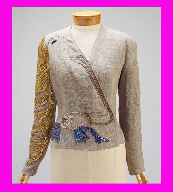 Jean Cocteau rajzolta ezt a szokatlan, aszimmetrikus mintát egy Schiaparelli estélyi kabátkához. A vállon megjelenő nő (hímzett) aranyhaja a jobb karon omlik le, válla-karja a kabátka záródását, kék kesztyűt tartó keze pedig derékrészt díszíti.