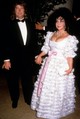 Elizabeth Taylor Larry Fortensky oldalán érkezett meg egy jótékonysági gálára a Beverly Hilton Hotelbe. A virágokkal díszített ruha, a rózsaszín szalag és a gyöngysor talán azokban az időkben kicsit túlzásnak tűnt, de Taylor mindig mert önmaga lenni – akkor is, amikor már nem a filmvászon közepén állt.