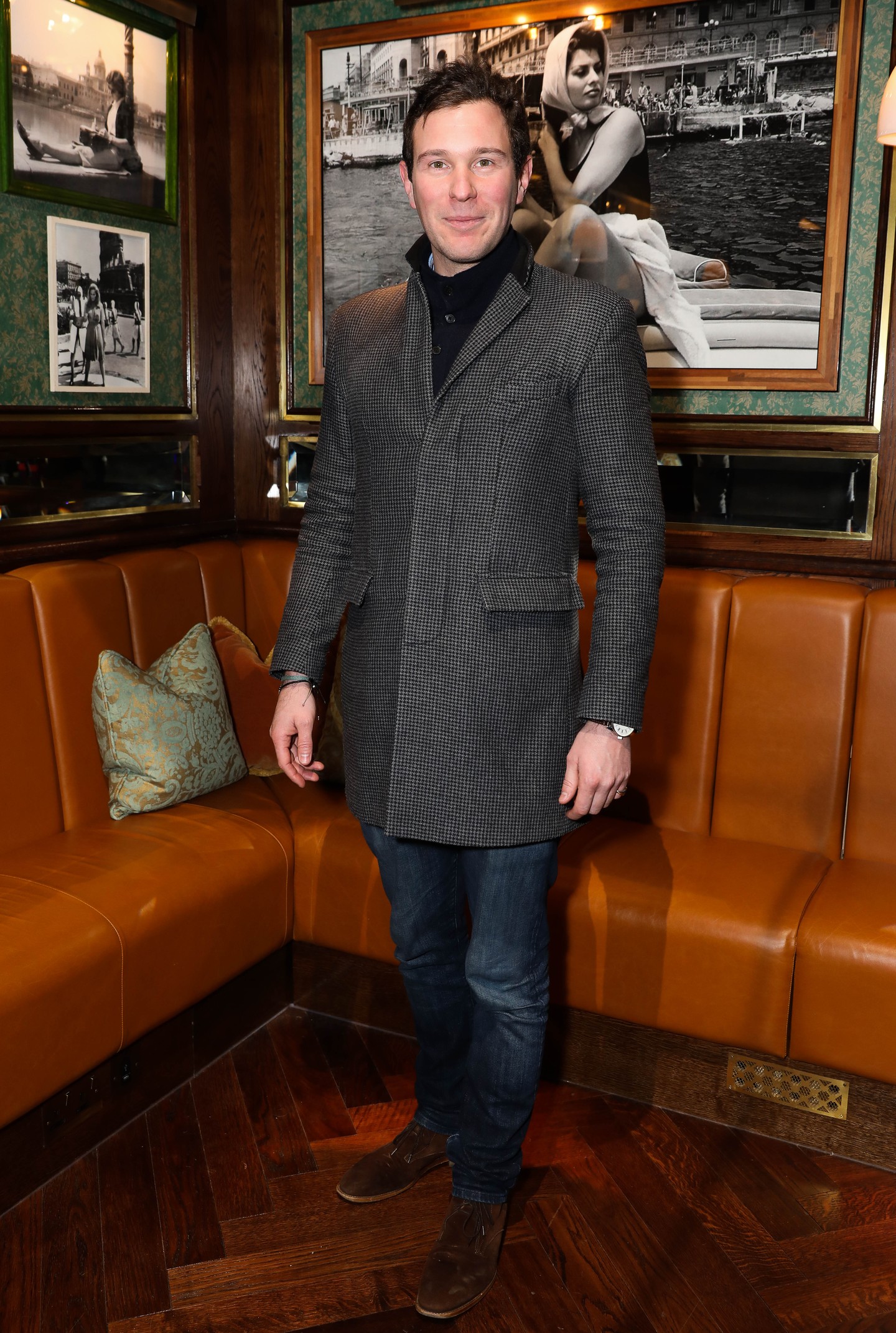 Eugénia hercegnő férje, Jack Brooksbank itt 2017 novemberében látható (akkor még a hercegnő párjaként), megjelenése kifinomult és divatos. Egy sötétszürke, halszálkamintás kabátot visel, amely letisztult vonalvezetésű, magas gallérral. Alá egy fekete garbót választott. A sötétkék farmer és a barna bőr bokacsizma tökéletesen kiegészíti megjelenését, egyensúlyt teremtve a hétköznapi és az elegáns megjelenés között. 