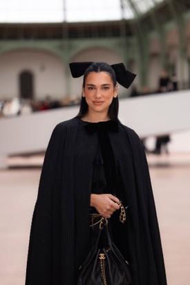 Dua Lipa bársonymasnival díszített, fekete köpenyében, fekete body-jában, valamint fekete szoknyájában éjkirálynőként tündökölt a fashion show-n.