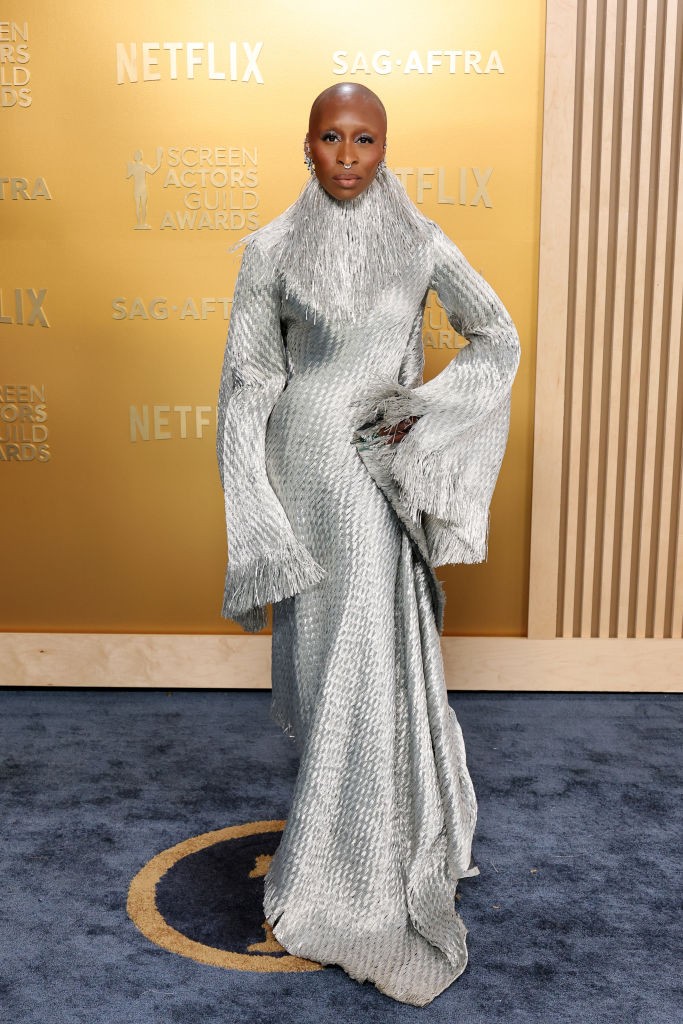 Cynthia Erivo egy lenyűgöző, ezüstös Givenchy ruhát viselt, amely Alexander McQueen 1997-es őszi/téli kollekciójából származik. A ruha aszimmetrikus kialakítású, magas nyakú, rojtos gallérral és széles ujjakkal rendelkezik, ezüstszínű, szőtt raffiából készült. Érdekesség, hogy ezt a ruhát először Debra Shaw modell viselte a kifutón 28 évvel ezelőtt. Erivo a megjelenését ezüst színű sminkkel és Bucherer ékszerekkel egészítette ki, körmeit pedig smaragdzöldre festette, utalva a Wicked című filmben alakított karakterére.