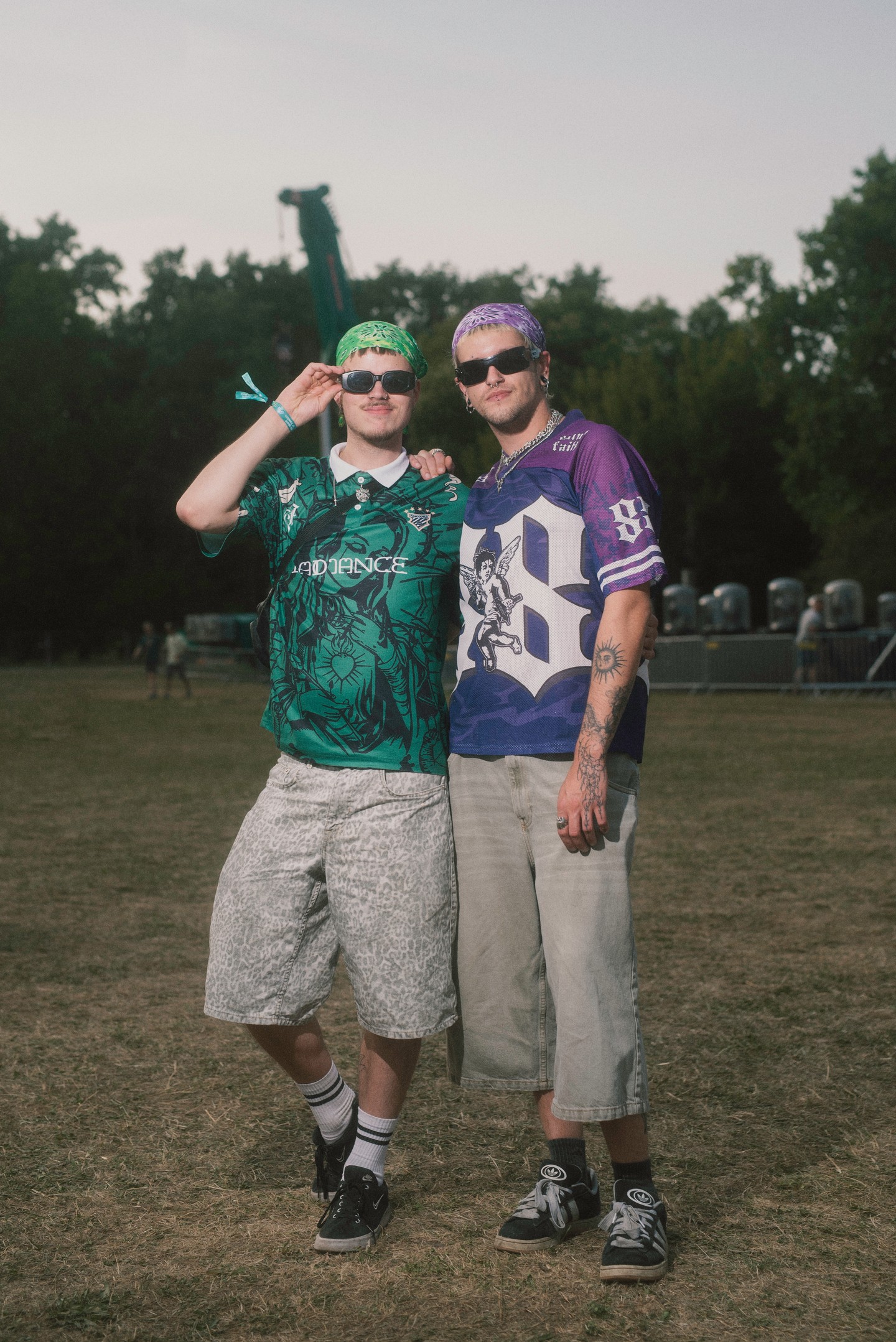 A 2020-as évek streetwear- és fesztiváldivatját idéző, tökéletes szettek: mindkét fiú oversize amerikaifoci-mezt választott, amelyet térdig érő, bő szárú nadrággal párosított. A fejpántként viselt kendők, a sportzoknik, a retró stílusú sneakerek és a fekete napszemüvegek egyszerre idézik a Y2K-hatást és a mai fesztivál-streetwear trendek nosztalgikus, mégis friss keverékét.