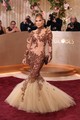 Ha valaki képes elegánsan viselni a költői túlzásokat, akkor az egyértelműen Jennifer Lopez, a meztelenruhák koronázatlan királynője. Jean-Louis Scherrer kreációja rengeteg áttetsző felülettel és kacér részlettel játszik, miközben sziluettjében is tovább emeli a tétet.