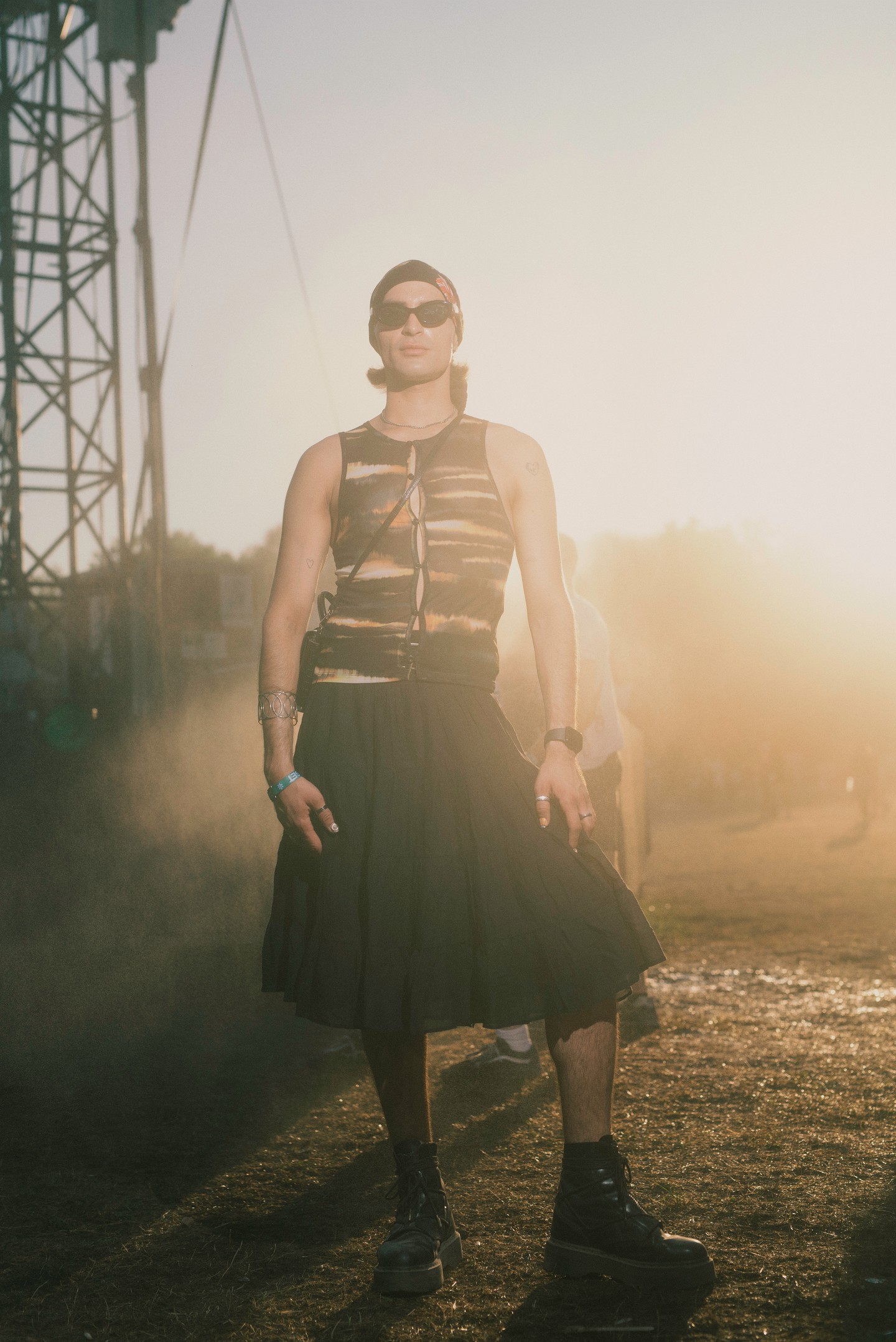 A divat iránti nyitottság és a szabadság tökéletes megtestesítője ez az összeállítás, amelyből a kísérletező szellem sem hiányzik. A bő szabású szoknya és a vastag talpú bakancs kontrasztját felül egy szorosan testre simuló, batikolt hatású, kivágásokkal díszített top egészíti ki, amely a Y2K-esztétikát idézi.