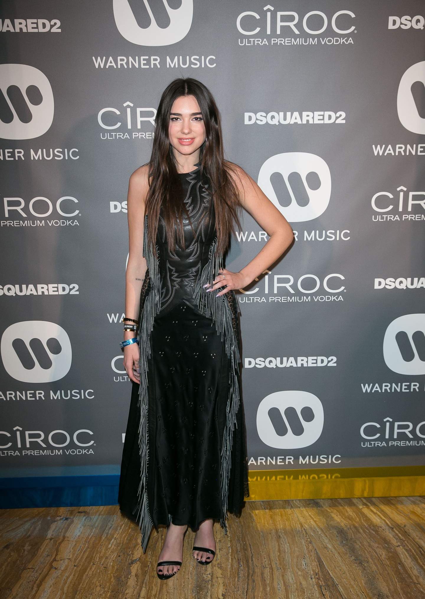 Dua Lipa 2016-ban a Warner Music brit Grammy-afterpartiján tűnt fel ebben a fekete, rojtokkal díszített bőrruhában, ami még jóval visszafogottabb volt a későbbi, merész és extravagáns megjelenéseihez képest.