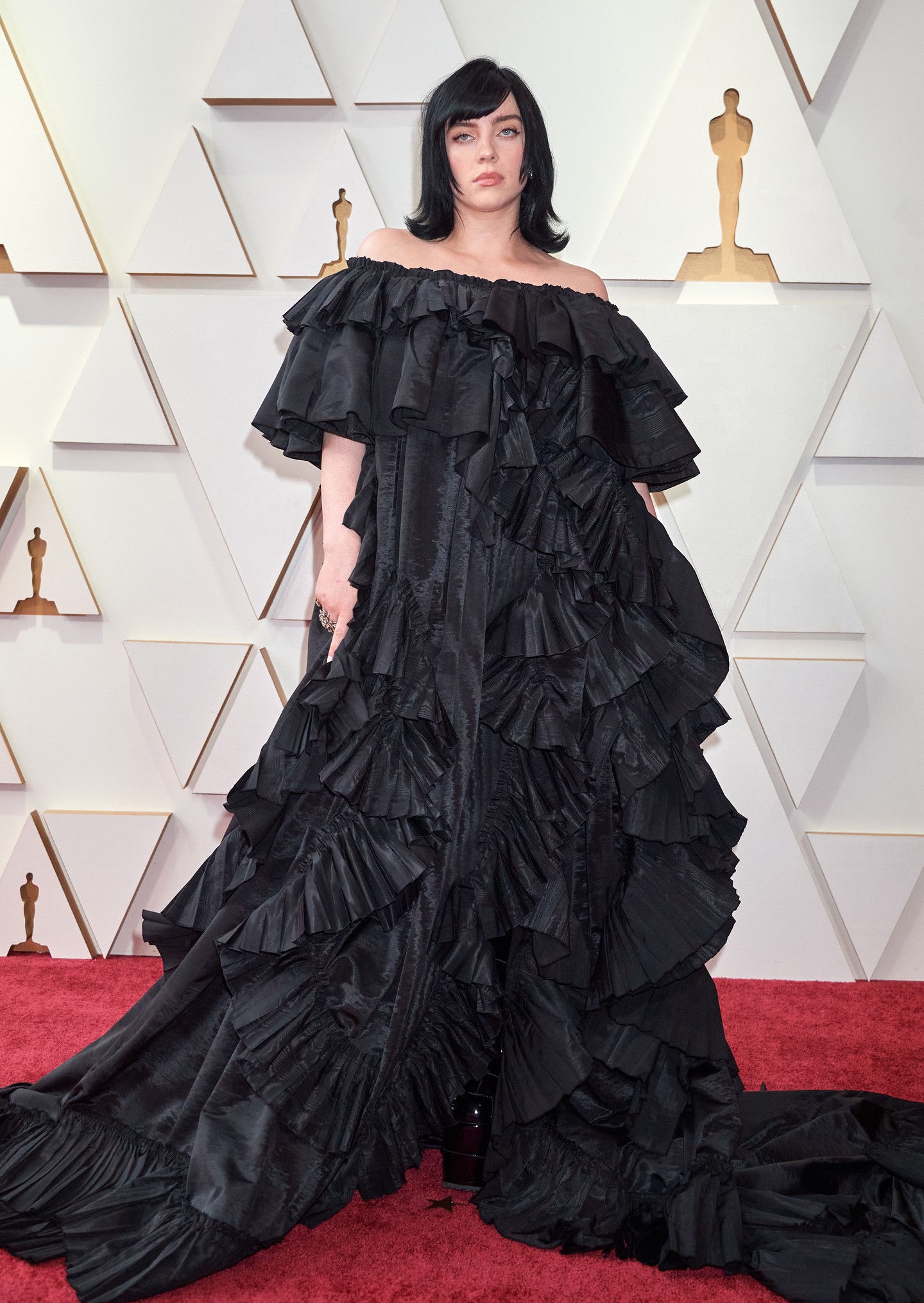 2022 - Lenyűgöző volt az Oscar-gála vörös szőnyegén az énekesnő egy fekete vállra szabott, fodros Gucci-ruhában.