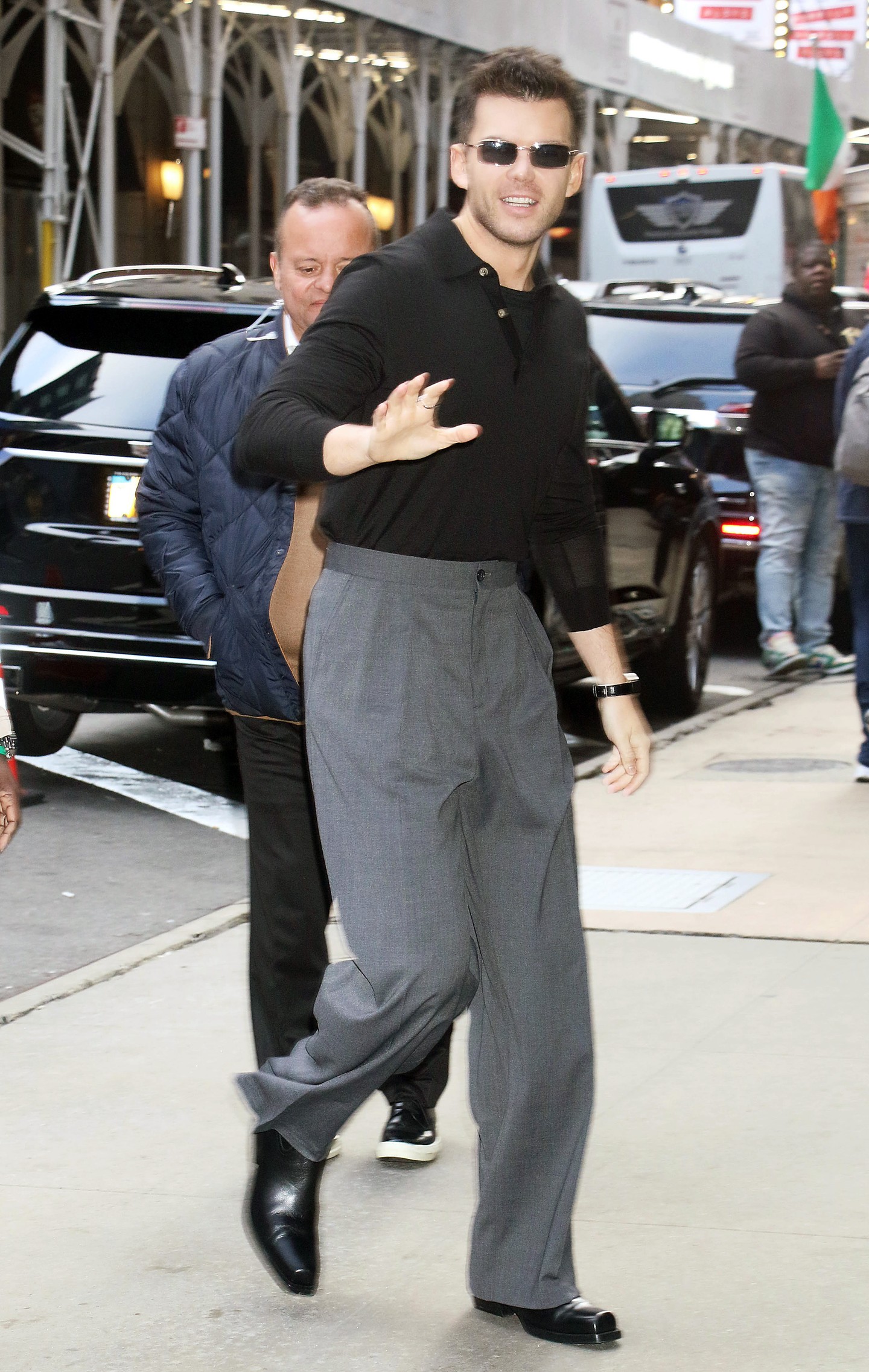 Mosolyogva intett a fotósoknak Luke Newton, amikor 2024. május 13-án megérkezett a Good Morning America stúdiójához New Yorkban. A Bridgertonben Colin Bridgertont alakító színész egy fekete felsőt és magas derekú, bő szabású nadrágot viselt, amely elegáns, mégis modern hatást keltett.