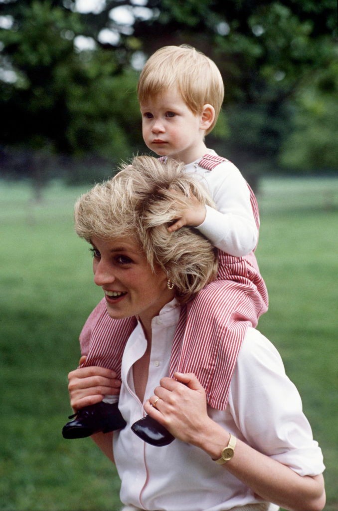 Diana hercegné, amint épp a vállán viszi Harry herceget a highgrove-i birtok zöld gyepén 1986 nyarán. A játékos közelség és Diana derűs arckifejezése arról árulkodik, mennyire élvezte az anyaság minden apró mozzanatát.