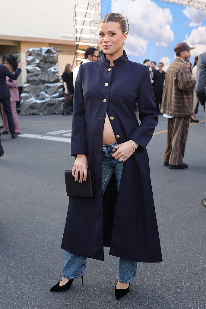 Sofia Richie Grainge a visszafogott elegancia helyett egy laza, mégis kifinomult megjelenést választott Tommy Hilfiger gardróbjából. Tengerészkék, aranygombos kabátot viselt, amely alól kivillant babapocakja, hozzá pedig egy farmernadrágot és hegyes orrú tűsarkút párosított. A lezser, de tudatosan felépített összeállítás igazi ínyencség volt a vörös szőnyegen. 