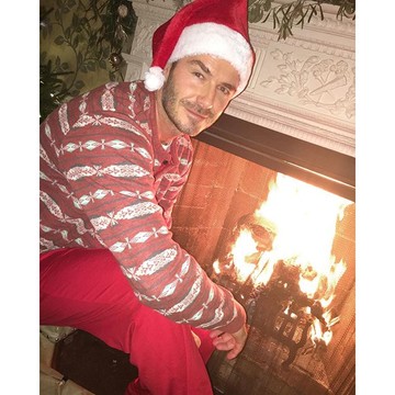 David Bekcham mosolyog a kamerának karácsonyi pizsijében és Télapó sapkájában.
