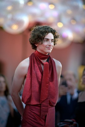 Timothée Chalamet mindig nagyot alkot a vörös szőnyegen – a színész legalább annyira divatikon, mint amennyire filmsztár. A Bones and All című film velencei premierjén egy bordó, szaténosan csillogó, ujjatlan és hátnélküli felsőben jelent meg, hozzáillő, szűkített nadrággal. A szettet a nyakába tekert sál tette teljessé. A megjelenést Chalamet barátja, Haider Ackermann tervezte, aki már többször felelt a színész extravagáns megjelenéseiért.