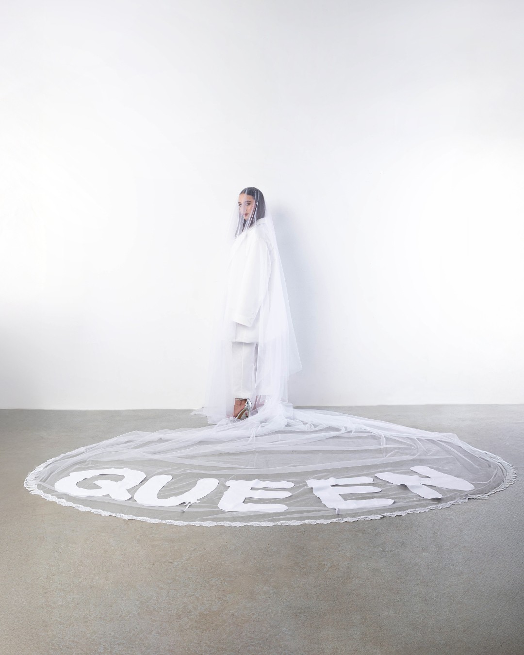 Queen and the Gang – Miss KK vezetésével egy modern, oversize szatén kosztüm és egy „QUEEN” feliratos fátyol készült.