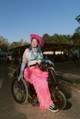 A vibráló, játékos és erősen fesztiválhangulatú megjelenésben, a pink rojtos nadrág, mintás bikinifelsővel és cowboykalappal van kombinálva. Az élénk színek, a tetoválások és a különleges kiegészítők eklektikus, extravagáns összhatást keltenek.