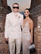 A márka idei, szicíliai fashion show-ján ismét magára vonzotta a tekinteteket: egy krémszínű selyem-szatén nadrágot viselt fehér zakóval, amit egy drágakövekkel kirakott, béka formájú brossal tett igazán egyedivé.   