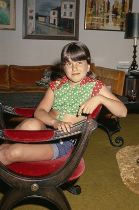 Jennifer Aniston otthonában, egy aranyos virágos felsőben és rövid farmernadrágban pózol. Akkoriban frufrut hordott, ami szépen keretezte babaarcát.