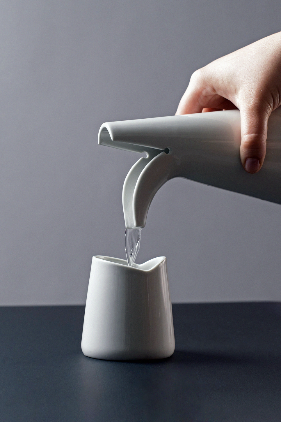 13.Nagy Sára Fruzsina: Novu porcelán készlet. A NOVU kancsó és pohár egy klasszikus csomóponti problémából merít ihletet, ahol egy test kettéválik. A V-alakú forma határozza meg karakterét, az 500 ml-es kancsó és a 250 ml-es pohár pedig egyszerre funkcionális és elegáns