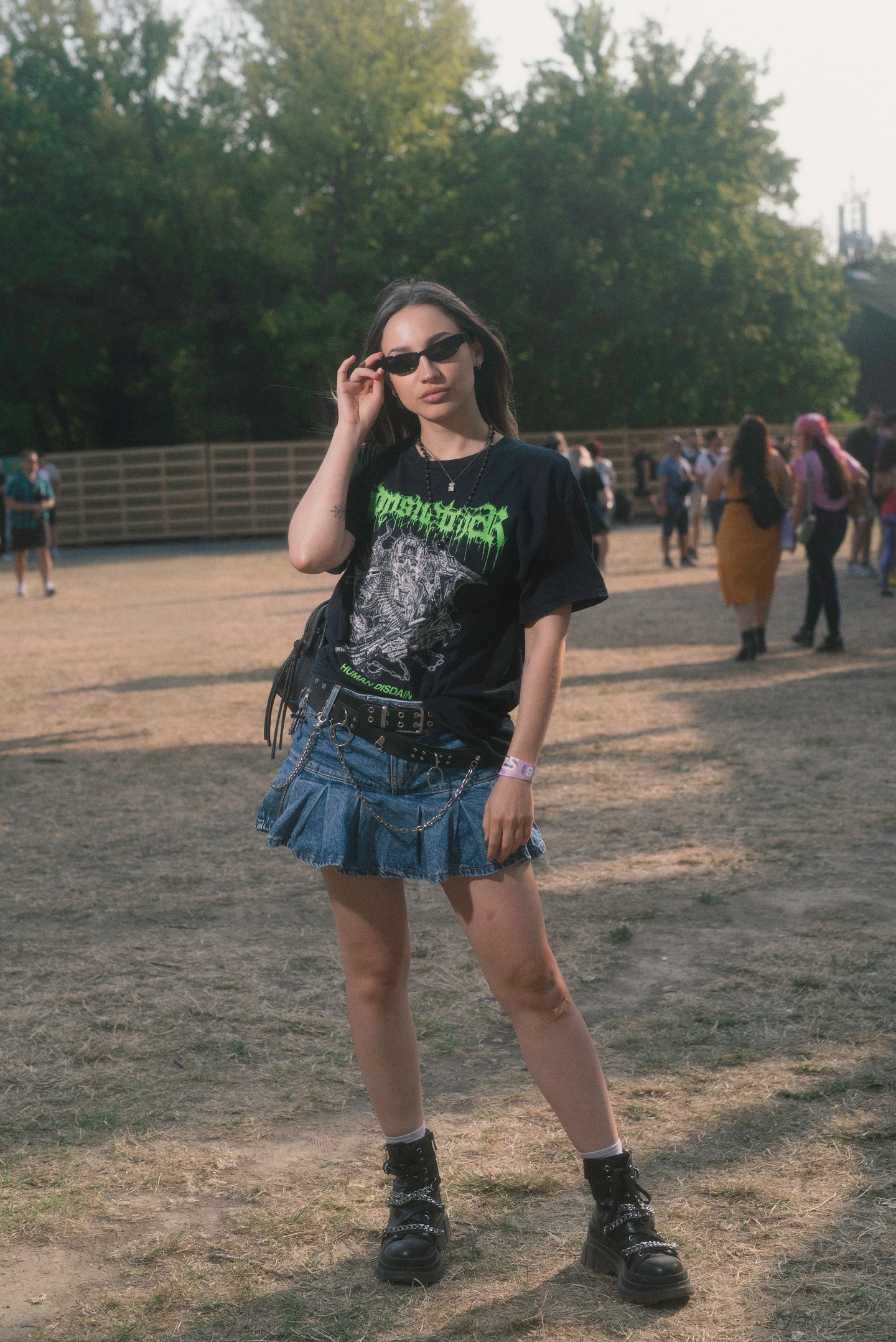 A farmer miniszoknya újra hódít – ráadásul stílusosabb, mint valaha. Bő pólóval, láncos kiegészítőkkel és szegecselt bakanccsal párosítva tökéletes választás a laza, mégis vagány megjelenéshez. A szettet az apró napszemüveg teszi teljessé, mintha a fesztiválozó épp egy zenekar backstage-éből lépett volna elő.