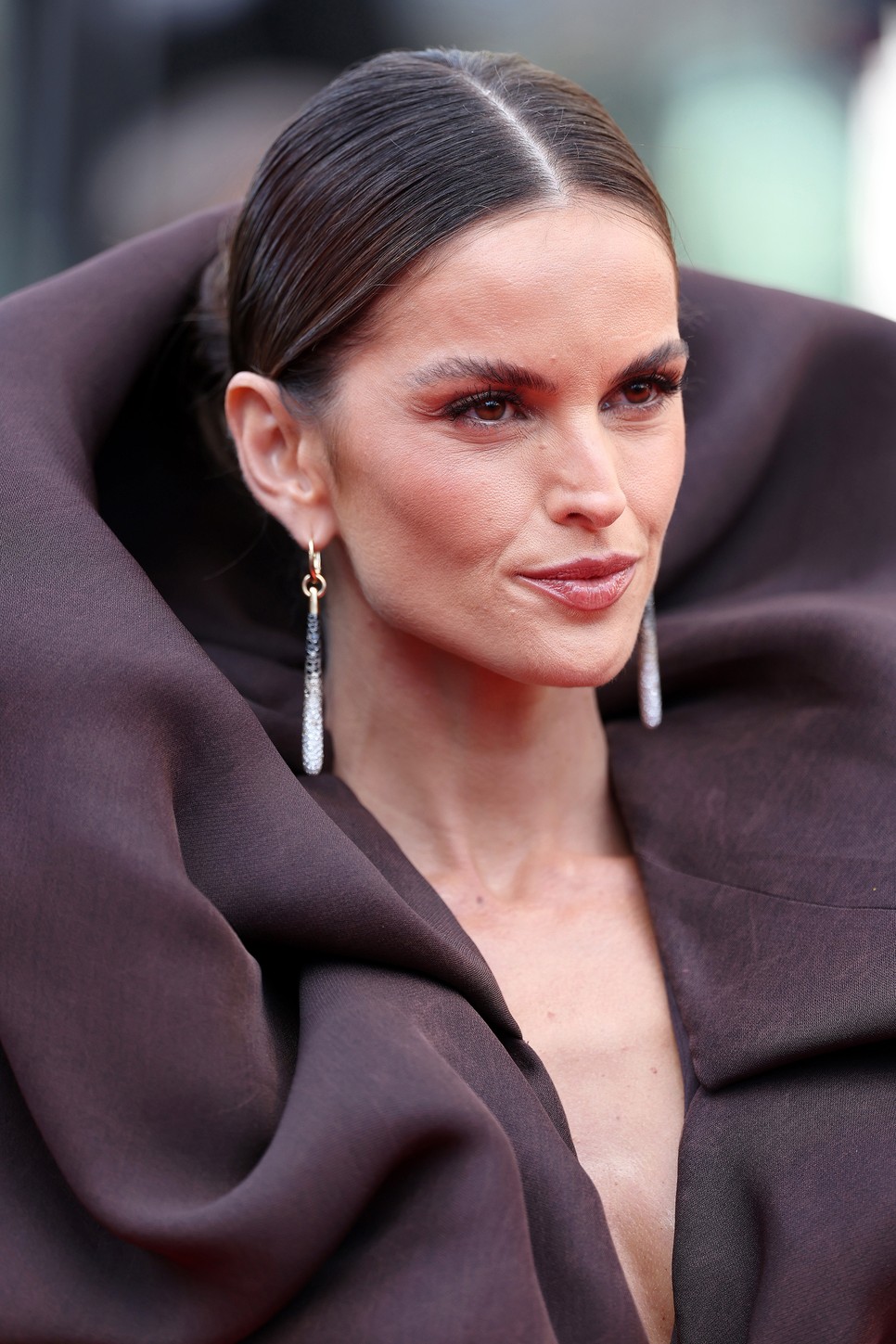 Isabel Goulart szupermodell a középen elválasztott, szoros konty mellett döntött