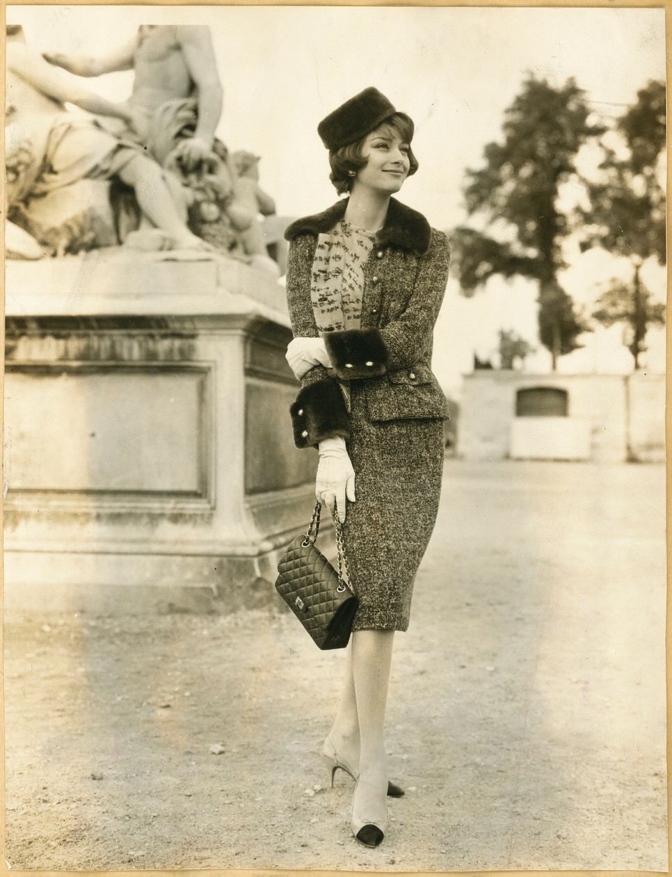 Marie-Hélène Arnaud a Chanel 1959-es őszi/téli kollekciójának tweed öltönyében, valamint Chanel cipőben, kezében a 2.55 Chanel táskával