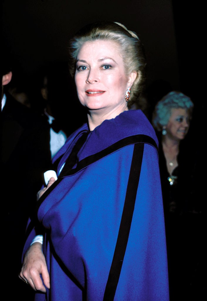 Ez a fotó a nyolcvanas évek elején készült az Egyesült Államokban. Grace Kelly egy élénk kék kabátot visel, haja kontyba tűzve, sminkje finom, mégis látványos. Letisztult és elegáns – pont, mint ő maga.