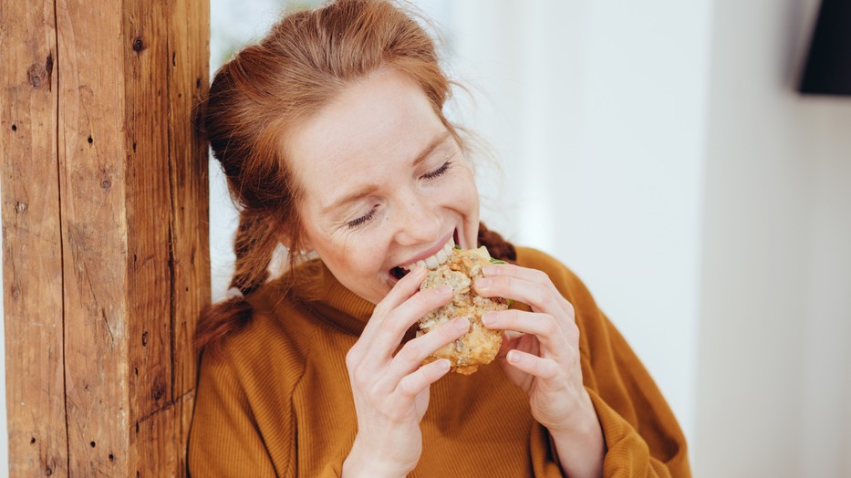 Hungry young woman taking a bite
