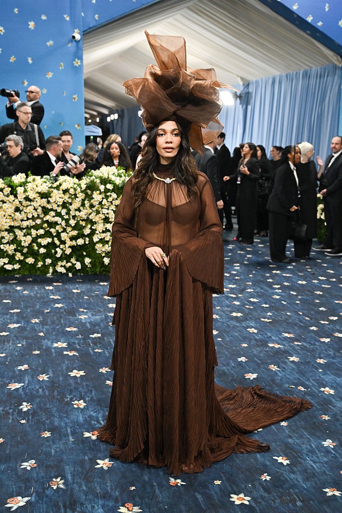 Aurora James úgy lebegett végig a Met-gála vörös szőnyegén, mintha egy másik dimenzióból érkezett volna. A fátyolosan áttetsző, földszínű ruha finom sejtelmességgel vonta be a testét, miközben a monumentális fejfedő koronaként magasodott fölé. A tervező és aktivista egyértelmű üzenetet közvetített: a merészség és az elegancia nem zárják ki egymást. Megjelenése egyszerre volt organikus, álomszerű és tiszteletet parancsoló – egy igazi vizuális manifesztum.