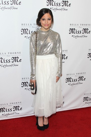 Jenna Ortega a Miss Me márka exkluzív megnyitóján debütált a vörös szőnyegen 2016-ban. A különleges alkalomra hófehér tüllszoknyát, ezüst, fémesen csillogó felsőt és fekete magassarkút választott. 