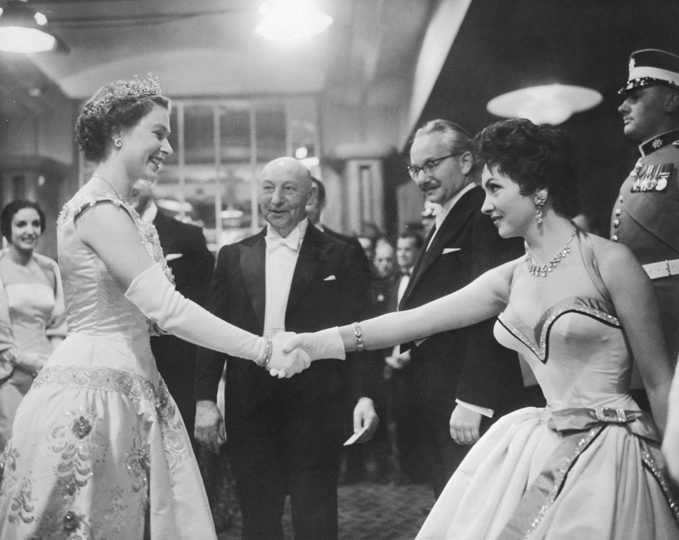  Gina and the Queen. London, England: Gina Lollobrigida curtseys and shakes hands with Queen Elizabeth II at the royal film premiere of Io Catch a Thief in London. The queen chatted with the Italian actress and other stars, including Ava Gardner, but showed no sign of feeling over Princess Margaret's decision not to marry Peter Townsend. Margaret, who usually attends the annual film performance, remained secluded at Clarence House.