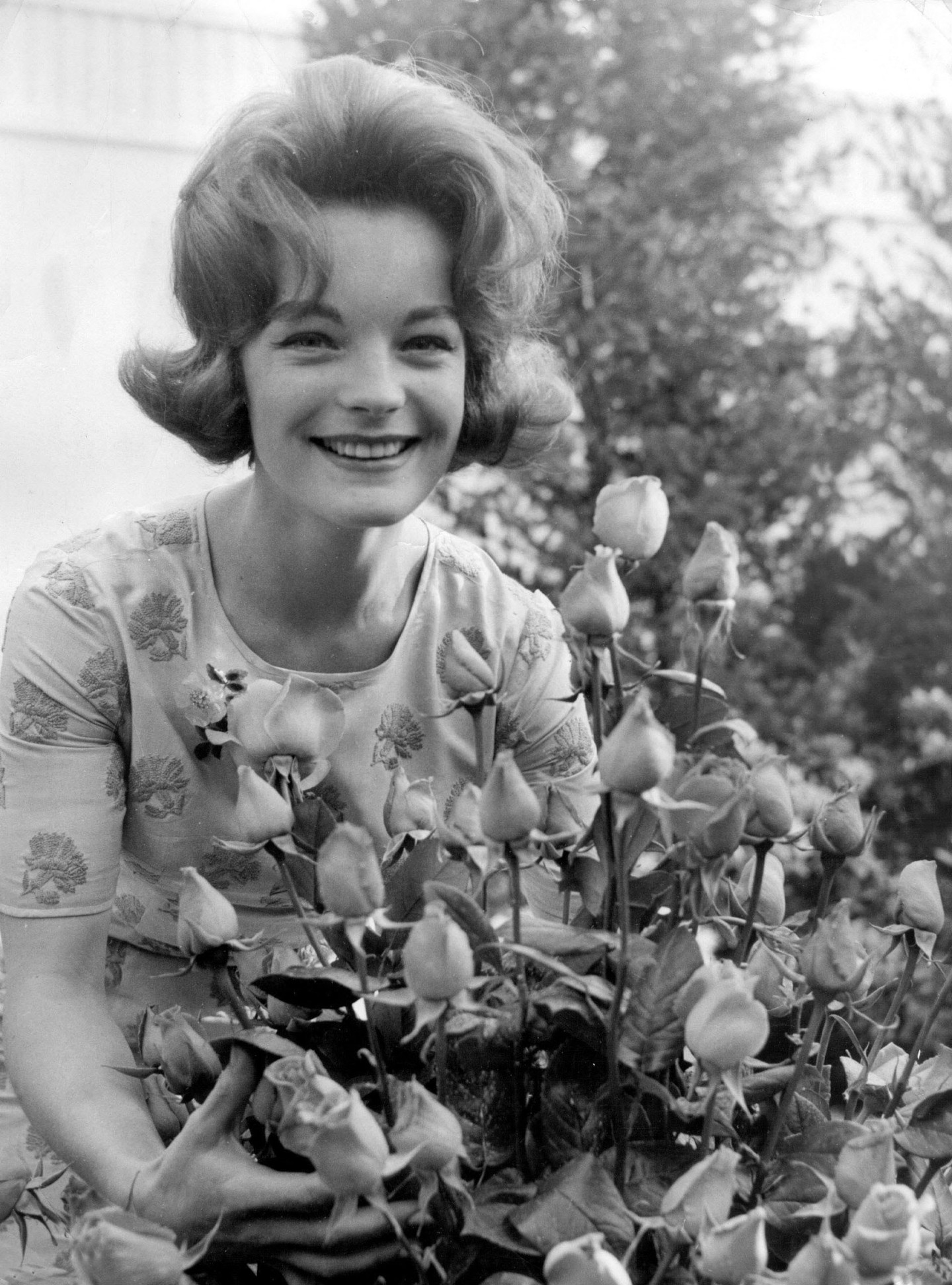 Romy Schneider 1961-ben, virágokkal körülölelve mosolygott a világra – ebben a pillanatban nem filmsztár volt, csak egy fiatal nő, aki észrevette az apró örömöket.