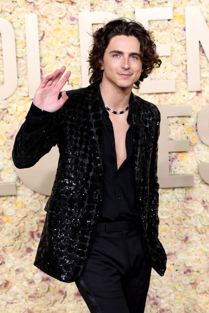 Timothée Chalamet egy olyan elegáns fekete flitteres  öltönyt vett fel, amelyet Celine Homme készített. A színész nyaklánca és gyémántokkal kirakott órája abszolút megkoronázta a megjelenést. Timothée Chalamet egyébként mindig nagyot alkot a vörös szőnyegen – a színész legalább annyira divatikon, mint amennyire filmsztár. Arról nem is beszélve, hogy ő a gendersemleges divat koronázatlan királya, hiszen számtalanszor hátat fordított már a maszkulin vonalaknak. 
