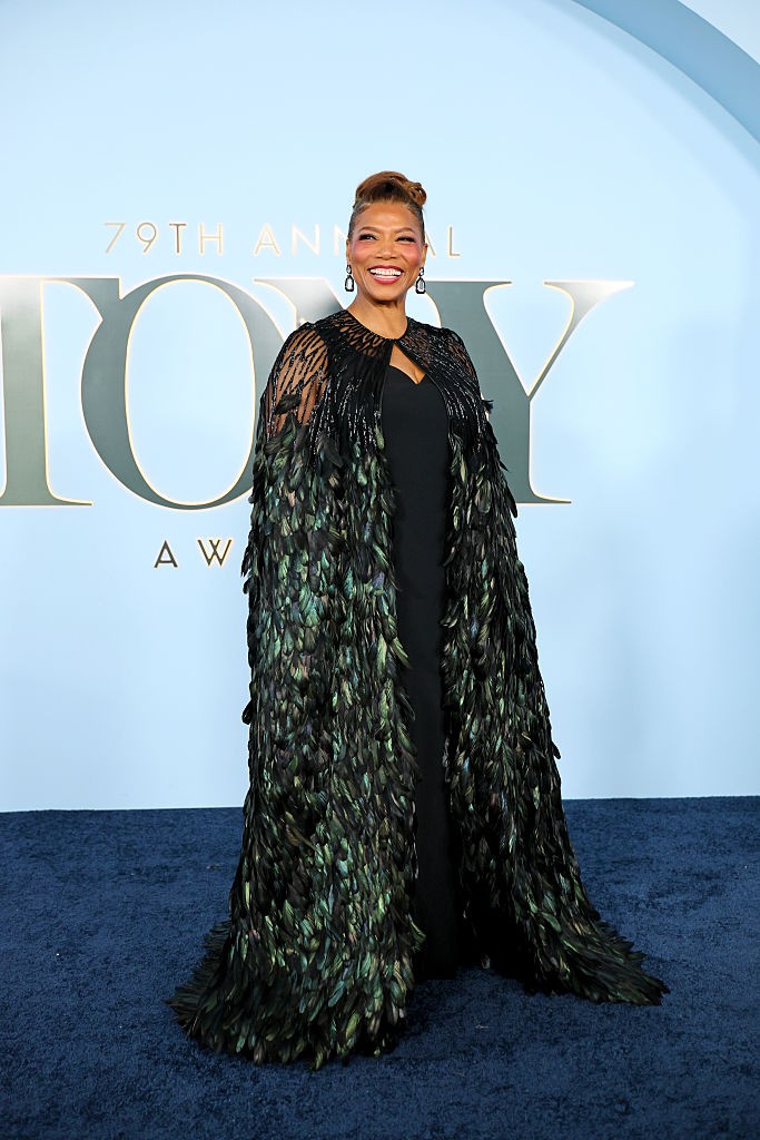 Queen Latifah királynői megjelenéssel hódította meg a vörös szőnyeget ebben a lenyűgöző Naeem Khan ruhakölteményben. A színésznő egy letisztult, elegáns fekete alapruhát választott, amely fölé egy egészen monumentális, földig érő köpenyt terített. Ez a különleges darab a vállrésznél finom, pókhálószerű fekete gyöngyhímzéssel indult, majd sűrűn varrt, méregzöld és kék árnyalatú tollakban végződött.  Az uralkodói összképet egy magasan feltűzött, elegáns konty és lógós fekete fülbevalók varázsolták hibátlanná.