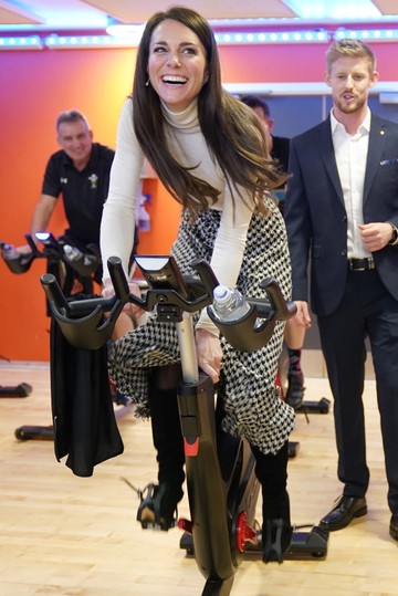 Katalin hercegné itt épp egy pörgős spin edzésen vesz részt a dél-walesi Port Talbotban található Aberavon Leisure and Fitness Centre-ben. A hercegné Vilmos herceggel közösen látogatott el az intézménybe, ahol nemcsak beszélgetett az ott sportolókkal, hanem maga is nyeregbe pattant – stílusos kockás szoknyában és mosolygós lendülettel tekerte végig a programot.