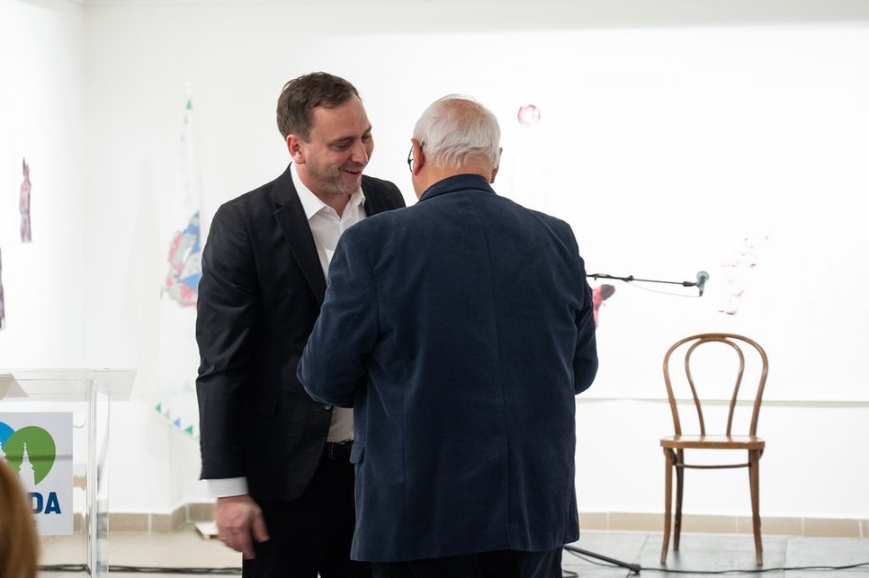 Őrsi Gergely, a II. kerület polgármestere jelképesen átadja a meNŐ kampány stafétáját dr. László Imrének, Újbuda polgármesterének, ezzel új fejezetet nyitva a kezdeményezés történetében