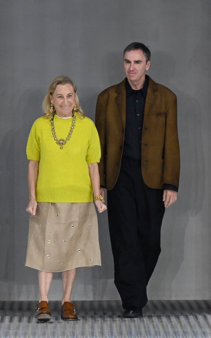 Raf Simons 2020 óta segíti Muccia Pradat kreatív társigazgatóként, a milánói divathéten is együtt léptek színpadra 2024 nyarán