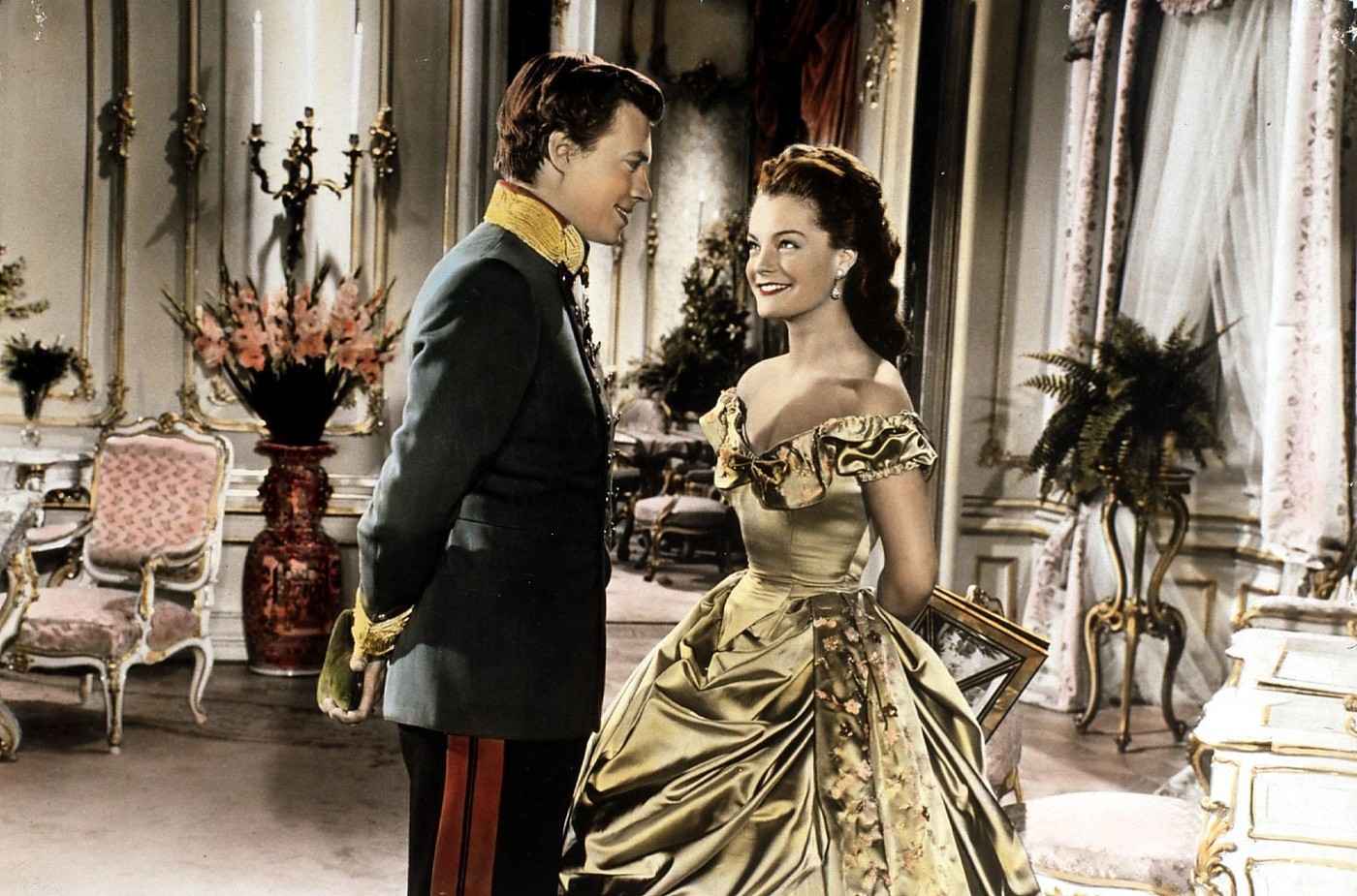 A Sissi-filmek belső jeleneteinek többségét nem valódi kastélyokban, hanem stúdióban épített díszletek között forgatták, méghozzá a bécsi Schönbrunn kastély stílusát alapul véve. A képen látható helyszín is egy ilyen díszlet volt, amelyet a Rosenhügel Filmstudios területén alakítottak ki. A gyönyörű aranyszínű ruhát Romy Schneider kizárólag ehhez a jelenethez viselte, és az egyik legnehezebb kosztümje volt a trilógia során: közel 9 kilót nyomott, a hímzések és selyemrétegek miatt. 