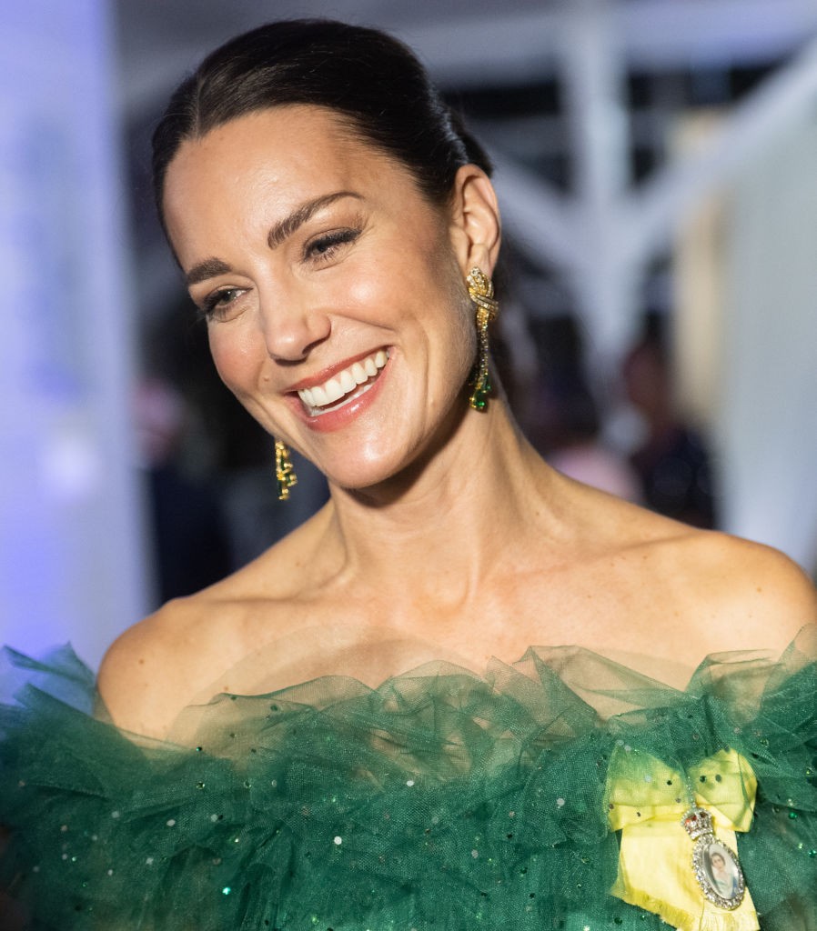 A királyi pár tavasszal a királynő nevében a Karib-térségbe utazott, II. Erzsébet platina jubileuma alkalmából. Katalin itt éppen Jamaikában, Sir Patrick Allen főkormányzó rezidenciáján tündököl, mesébe illő ruhakölteményben. A gyönyörű smaragdzöld estélyi (Jenny Packham divattervező munkája), a királynő smaragd fülbevalóival éd karkötőjével kiegészítve nem csak elképesztően jól néz ki, de a jamaikai zászló színeihez is passzol. 