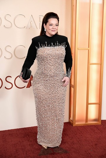 Az 55 éves Melissa McCarthy egy testhez simuló, csillogó estélyit választott az alkalomra, amely a reflektorok fényében szinte ragyogott. Megjelenését gyémánt fülbevalókkal, hegyes orrú, fémfényű magassarkúval és egy elegáns fekete borítéktáskával egészítette ki. Frizuráját dús, félig feltűzött formában viselte, sminkje pedig természetes ragyogást adott az összhatásnak.