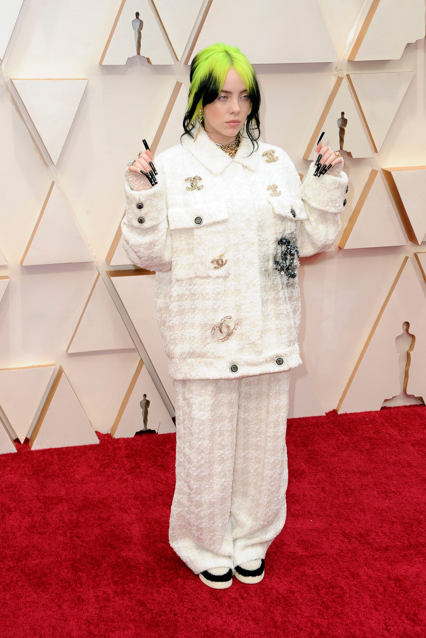 2020 - Chanel Chic! Arany és fekete Chanel brossokkal a kabátján, és fehér csipkekesztyűjével Billie Eilish csodálatosan nézett ki Oscar-díjas debütálása alkalmával. A túlméretezett tweedruha szintén egy egyedi tervezés volt.