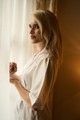 A sejtelmes felvételen a meleg tónusú háttérvilágítás gyönyörűen kiemeli a modell arany fürtjeit 
