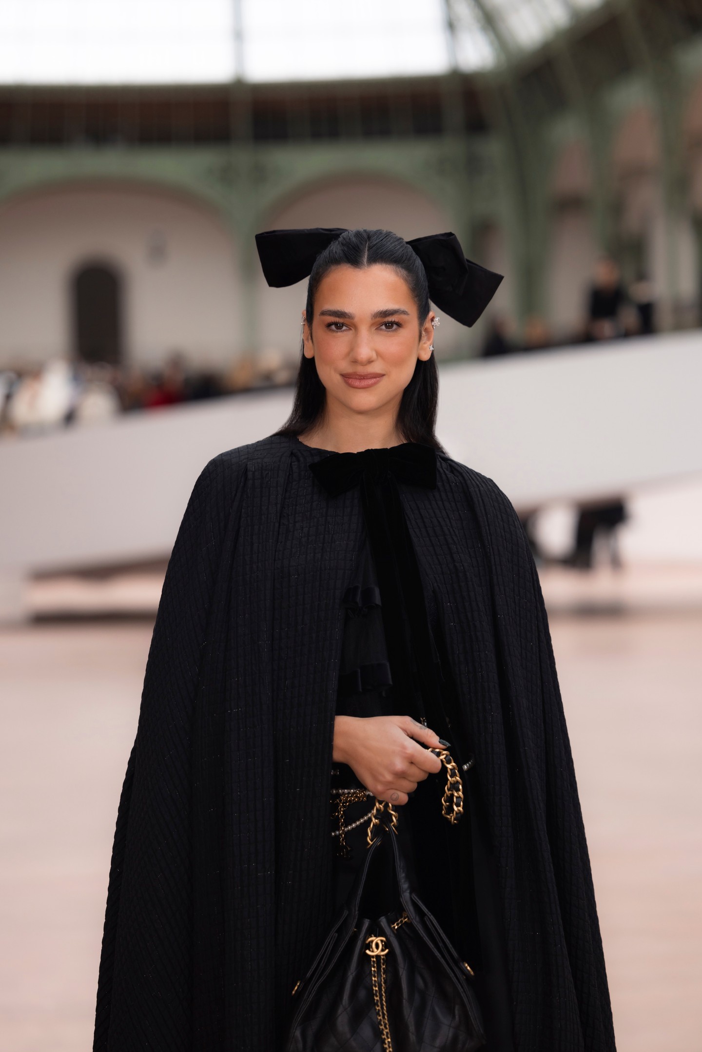 Dua Lipa bársonymasnival díszített, fekete köpenyében, fekete body-jában, valamint fekete szoknyájában éjkirálynőként tündökölt a fashion show-n.